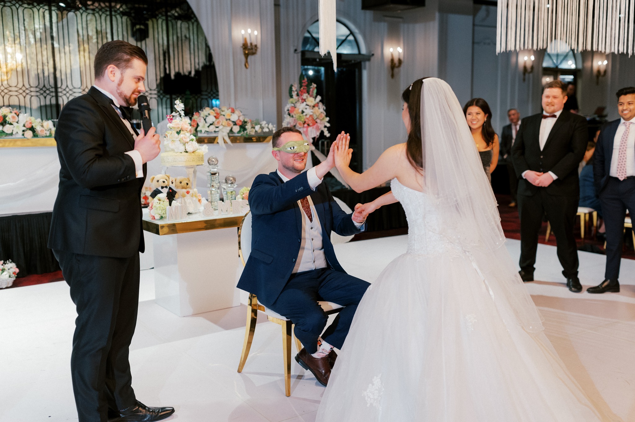 Bride and blindfolded groom playing wedding reception game
