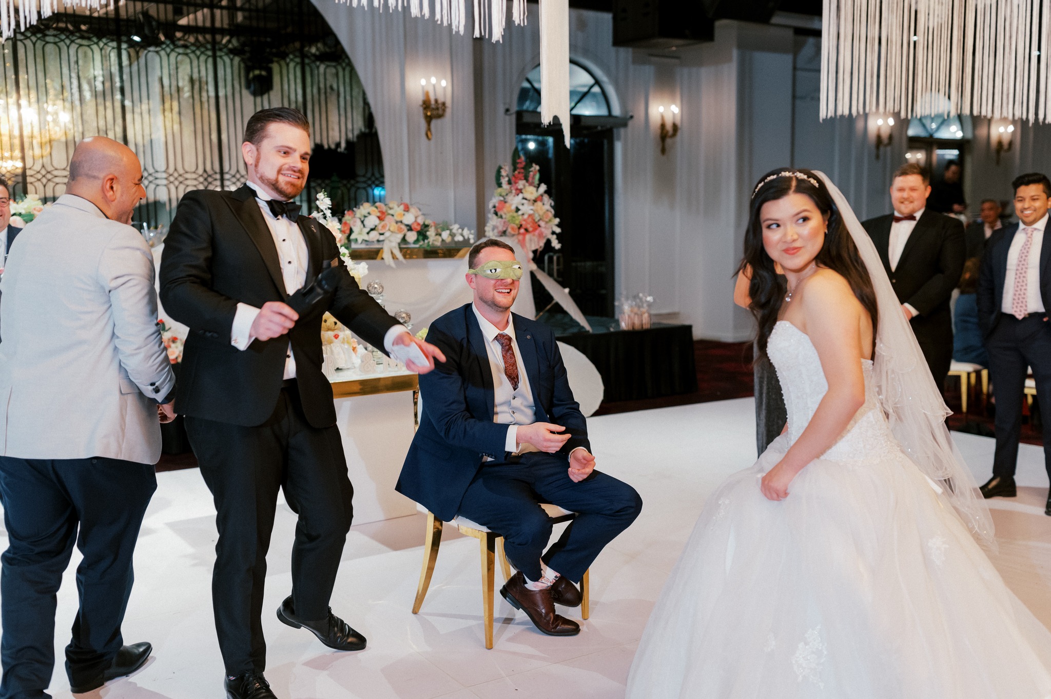 Bride and blindfolded groom playing wedding reception game