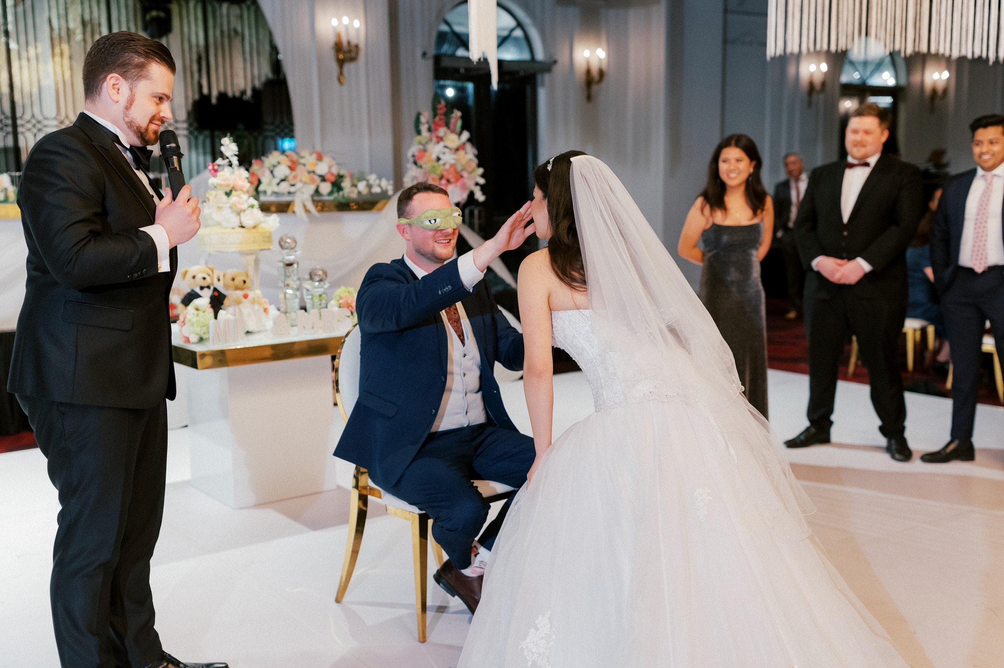 Blindfolded groom touching bride during wedding reception game