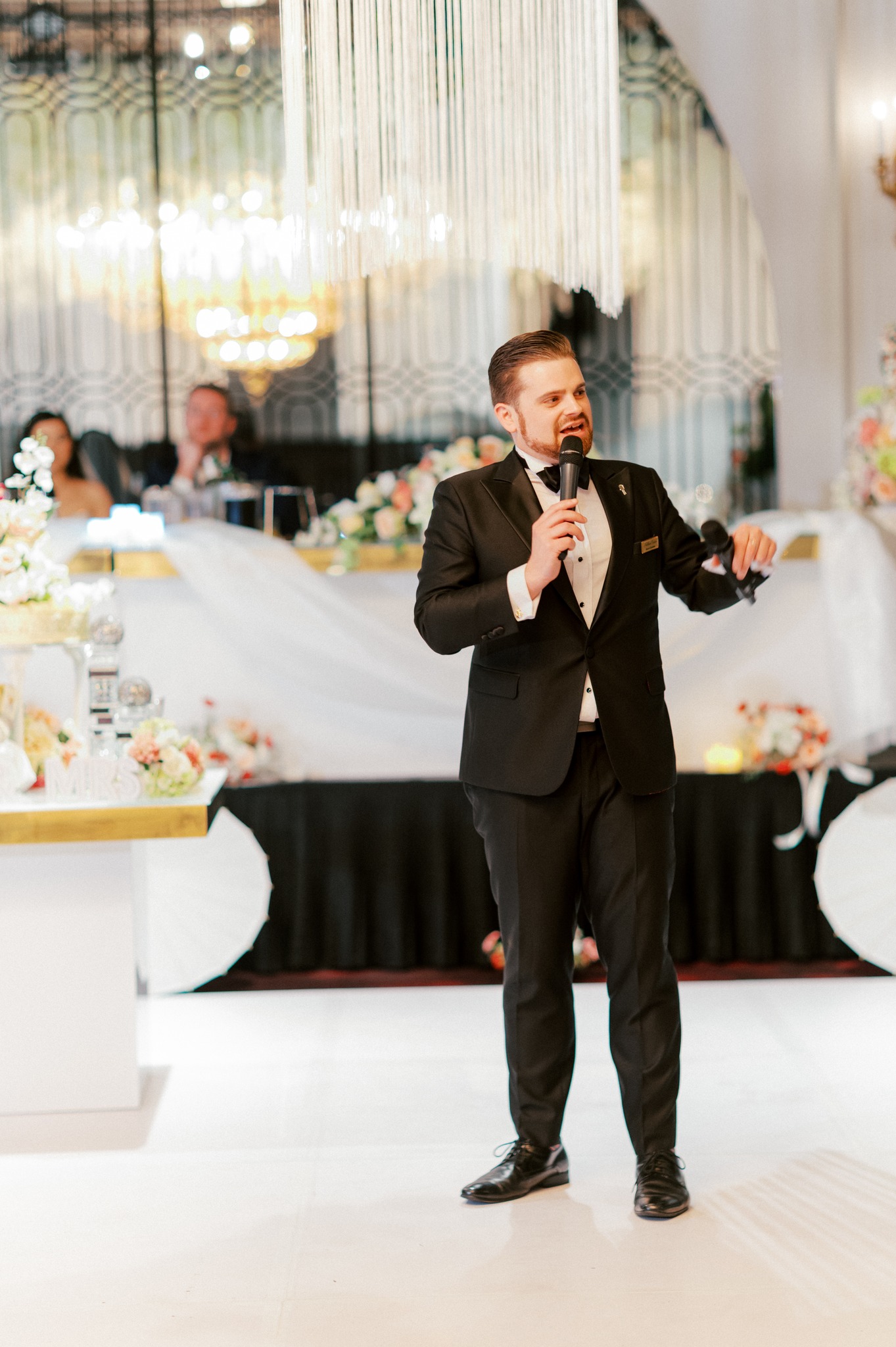 Man giving wedding speech in tuxedo reception venue