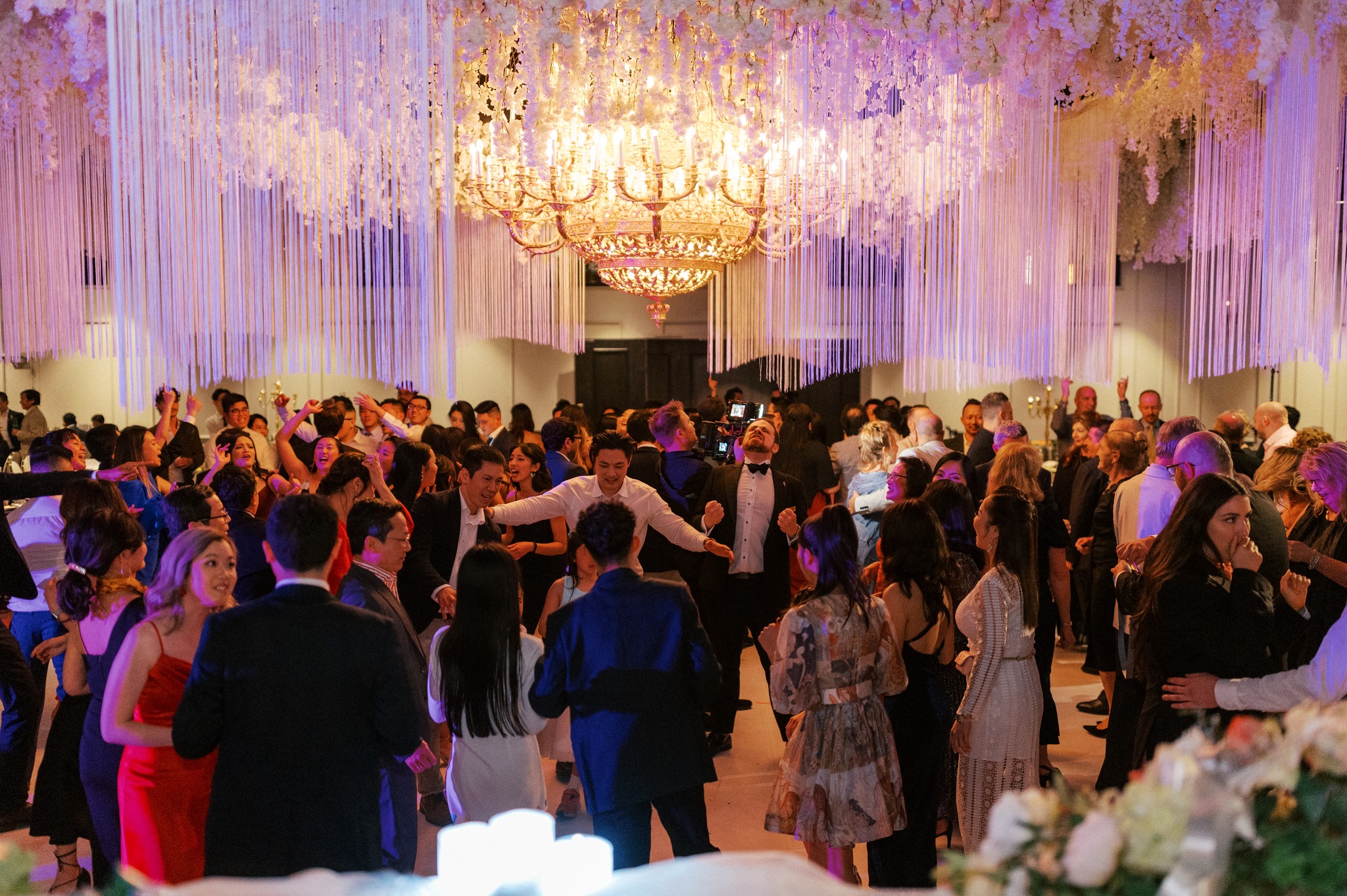 Guests dancing beneath chandelier at elegant wedding reception