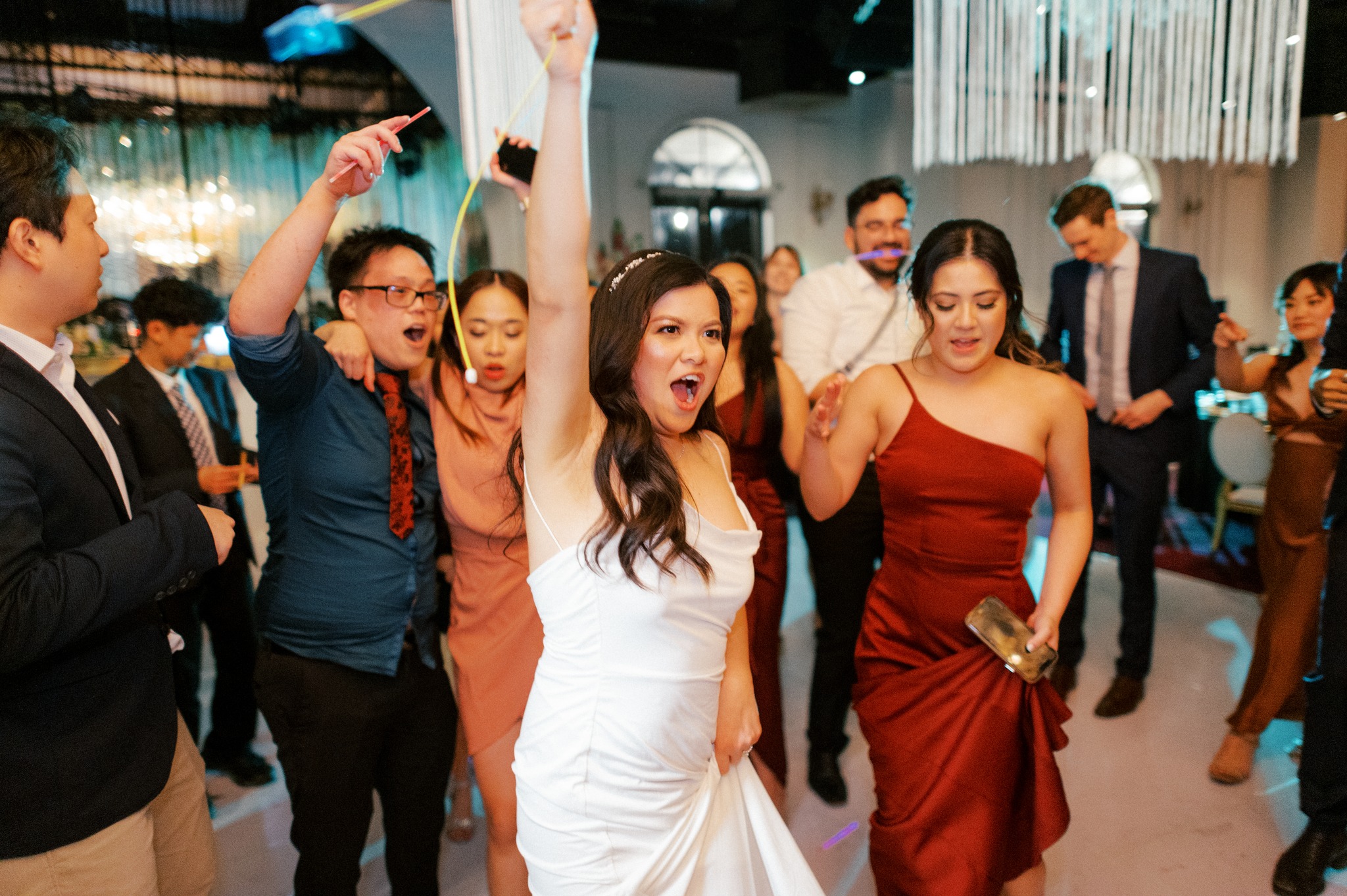 Bride celebrating on dance floor with guests cheering