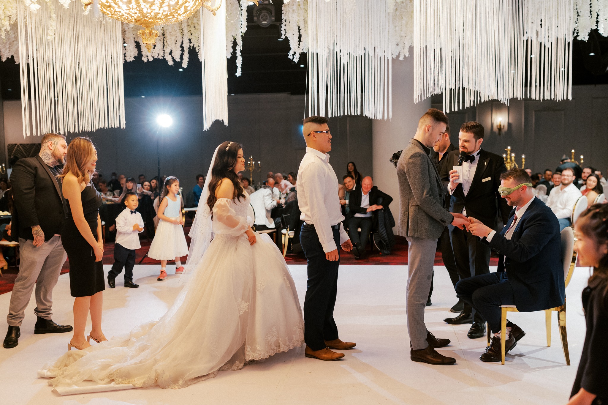 Groom blindfolded placing ring during wedding reception game