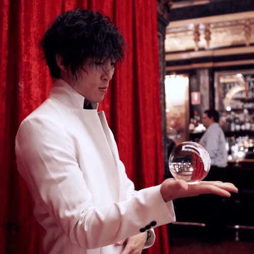 Man in white suit holding crystal ball indoors