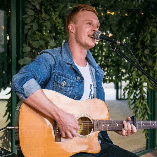 Man singing and playing acoustic guitar outdoors